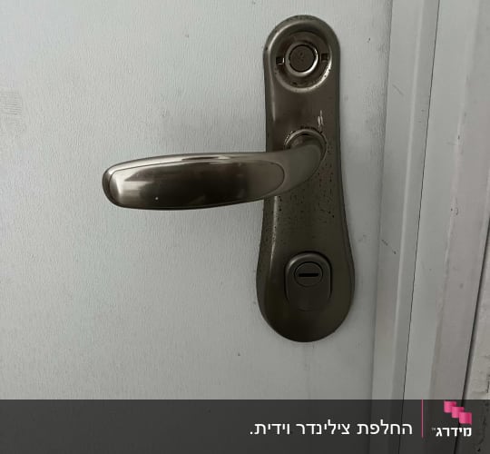 ידית דלת מתכתית עם מנעול על דלת לבנה